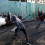 Masked protesters clash with riot police during a march marking the anniversary of the Tlatelolco massacre in Mexico City, Wednesday, Oct. 2, 2013